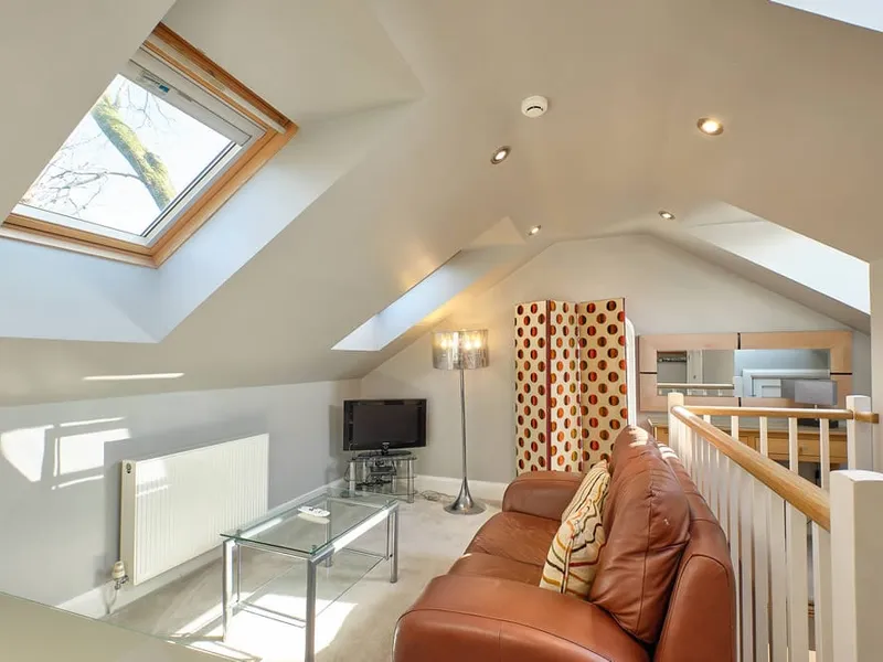 The mezzanine sitting room of The Suite with leather sofa and skylight