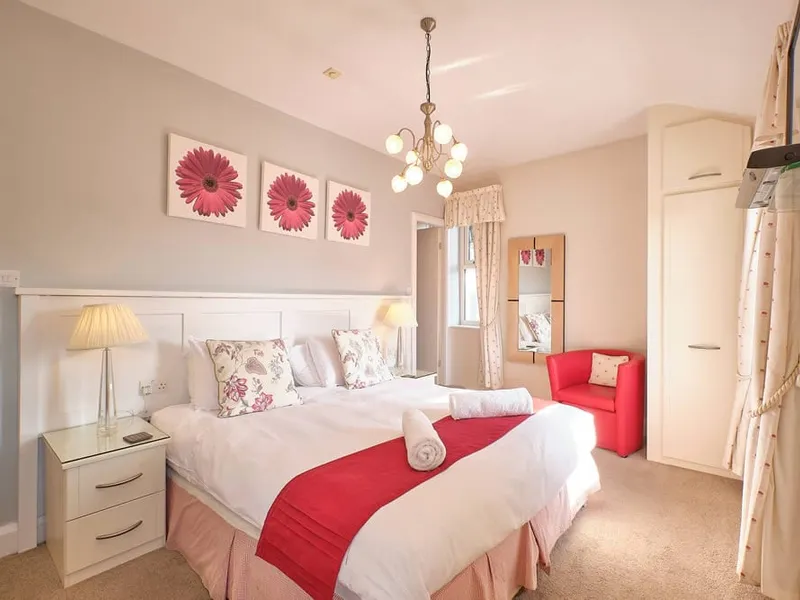 Room One at Grassington Lodge with a red throw and pink artwork