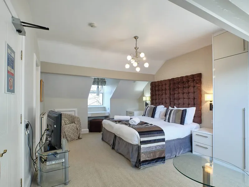 Room Eight at Grassington Lodge with a red headboard and sloping ceiling