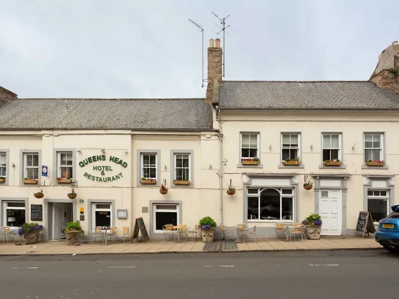 The Queens Head Hotel on Sandgate, Berwick-upon-Tweed, a cream-painted terrace with hanging baskets