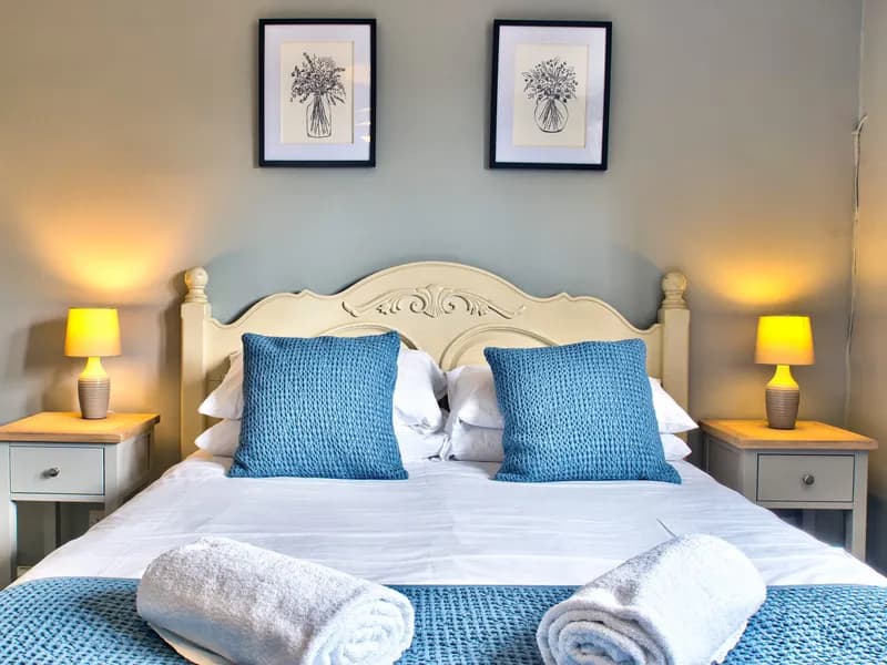A king-size double room at The Vines with a white carved headboard and blue cushions