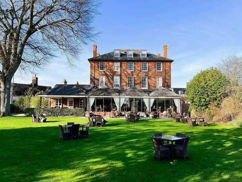 The Riverside House Hotel, a red-brick Georgian house with a conservatory, seen across the lawn