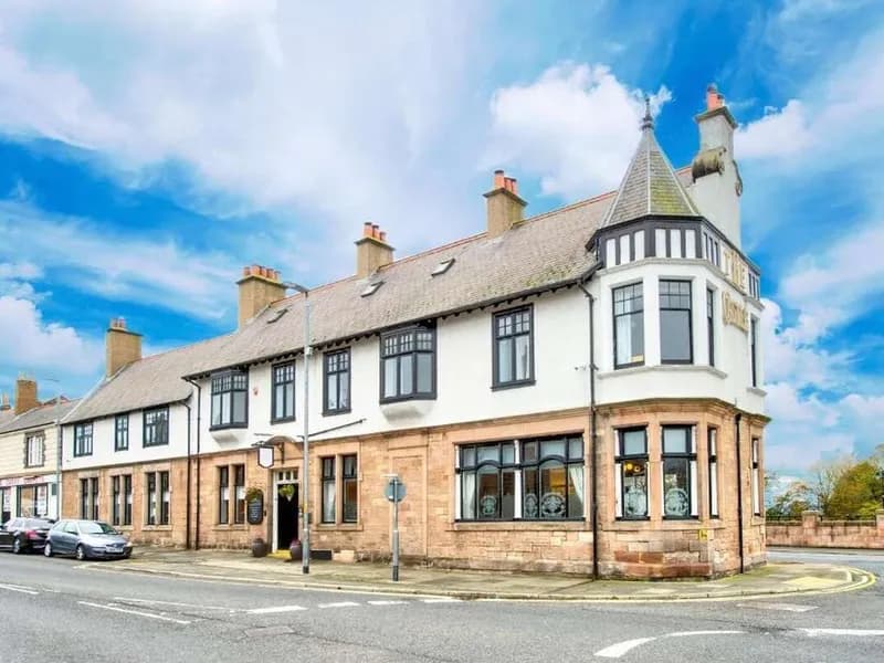 The Castle Hotel on Castlegate, Berwick-upon-Tweed, a stone corner building with a turret under a blue sky